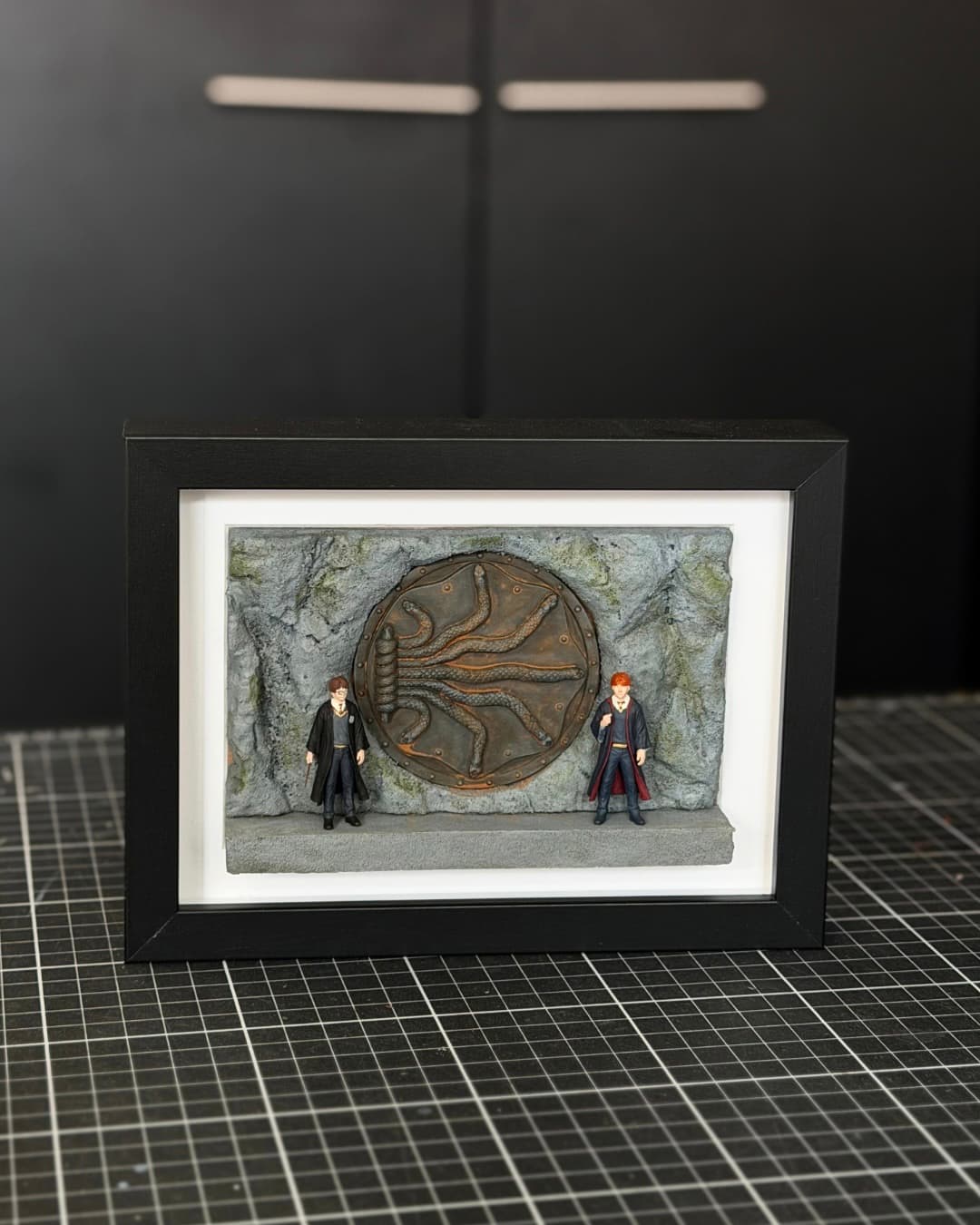 Framed miniature of the Chamber of Secrets door with two young wizard figures