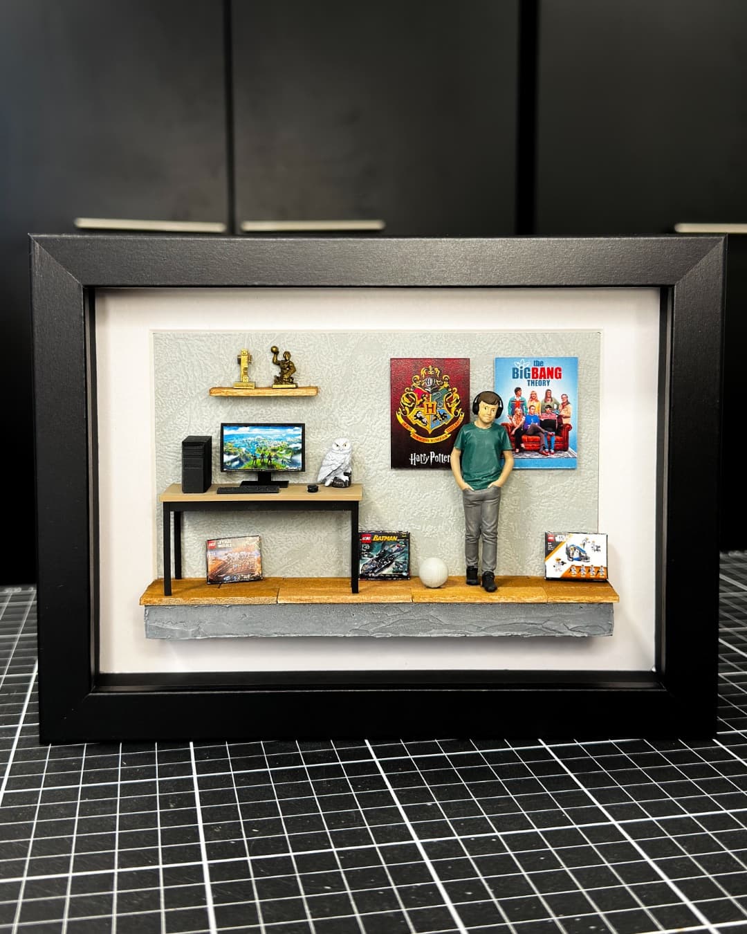 Framed miniature of a gamer's room with a desk, a computer and film posters