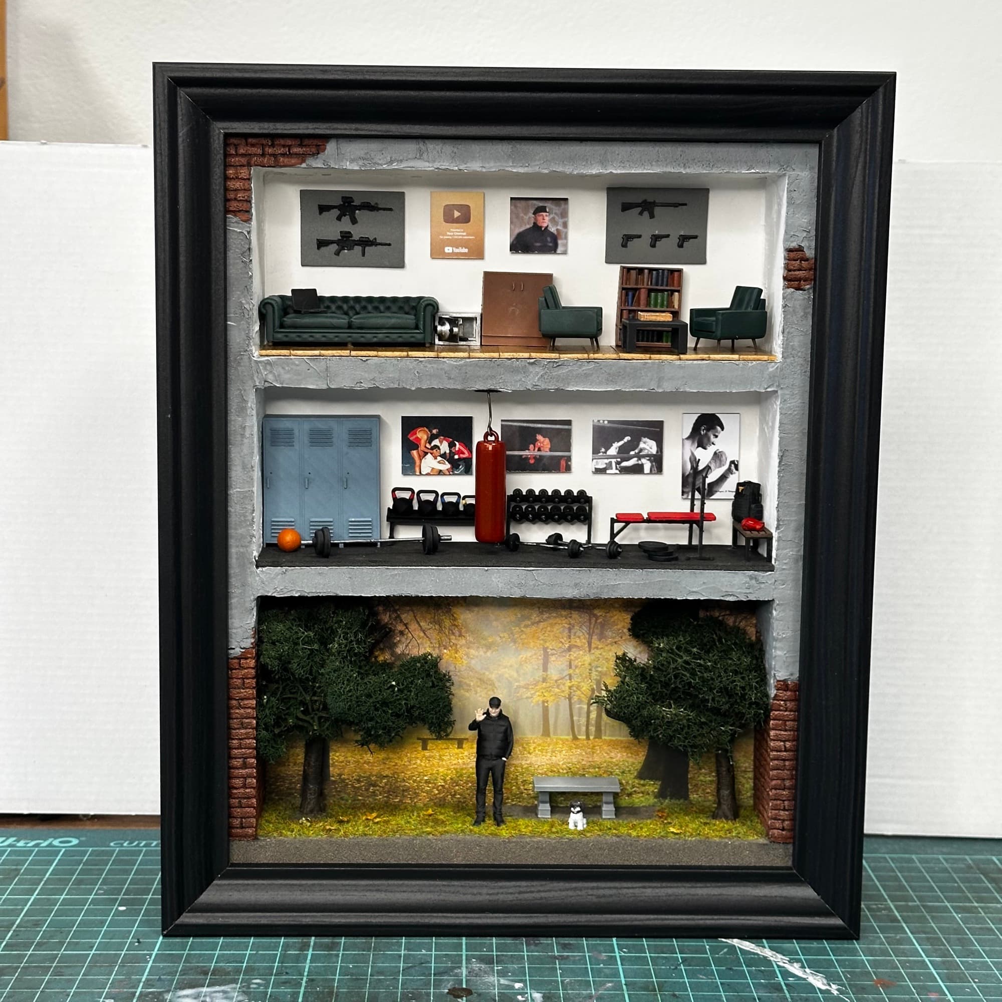 Framed three-level miniature with a lounge, a boxing gym and a man with a dog in an autumn forest