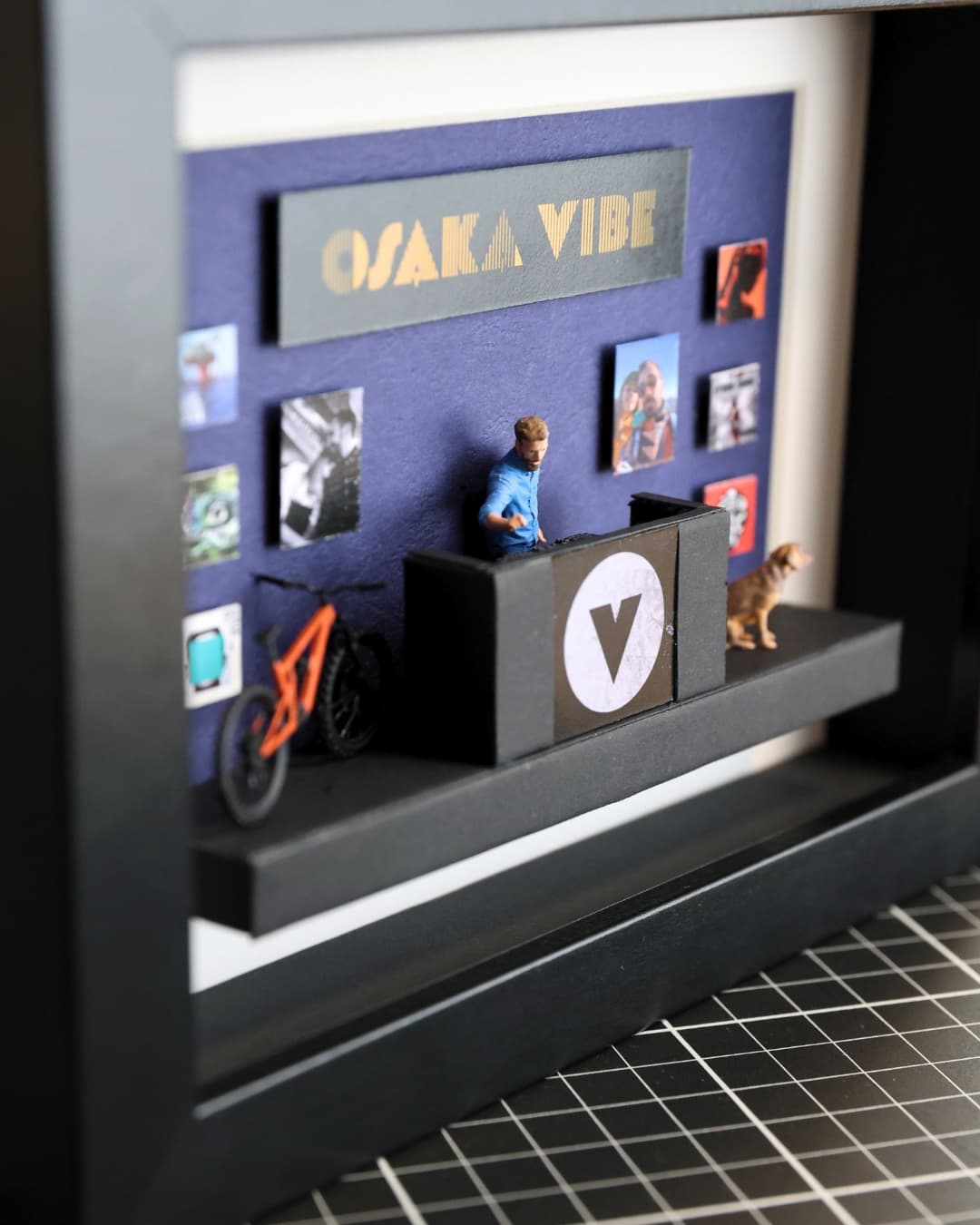 Close-up of a framed miniature with a DJ at his booth, a mountain bike and a dog