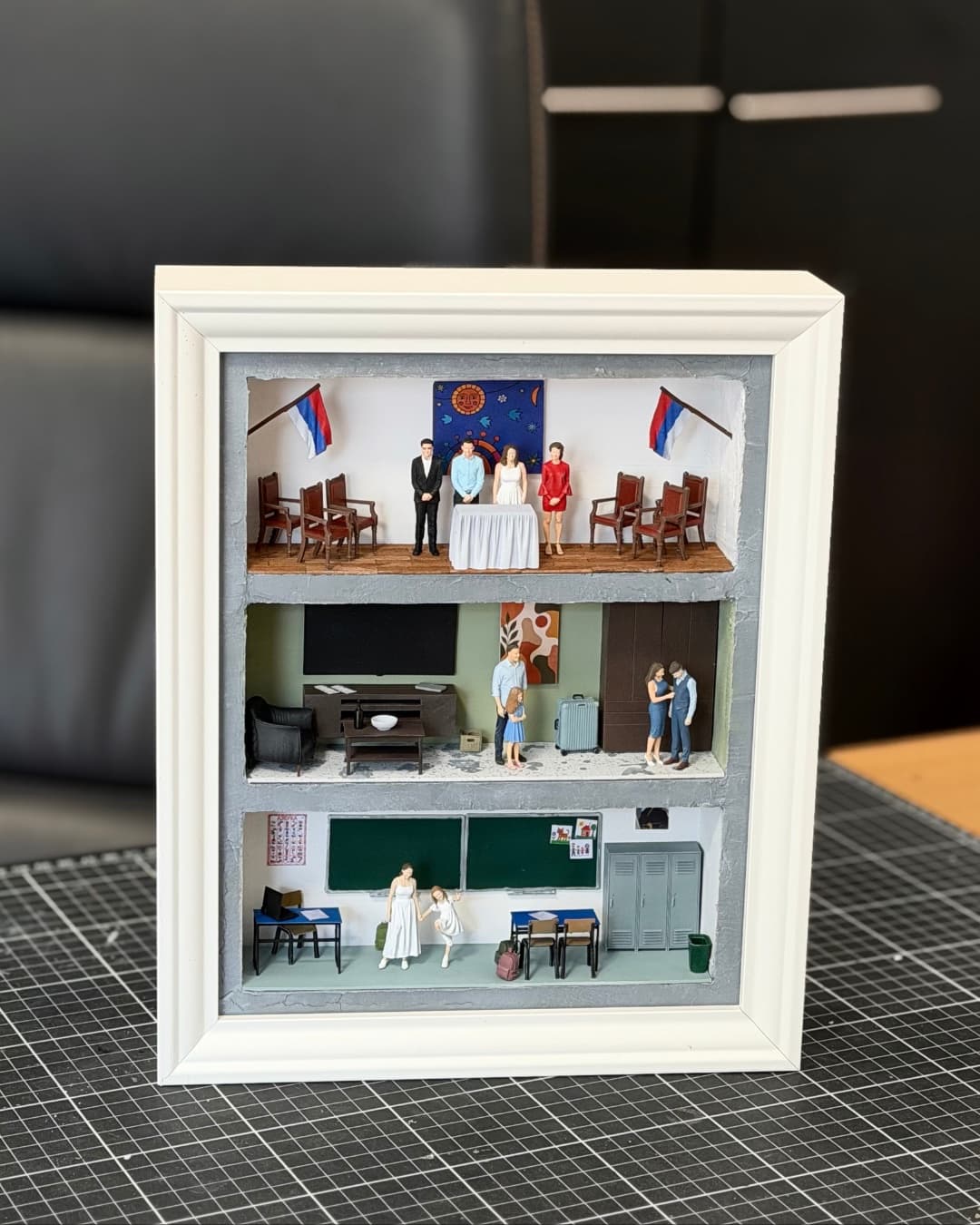Framed three-level miniature with a registry office wedding, a living room and a classroom