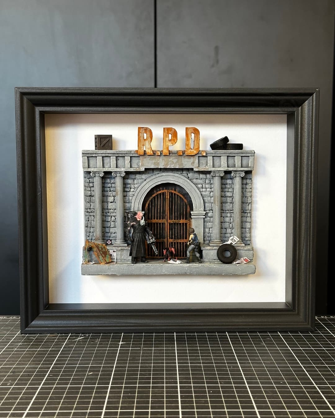 Framed miniature of the R.P.D. police station gate from Resident Evil with two figures