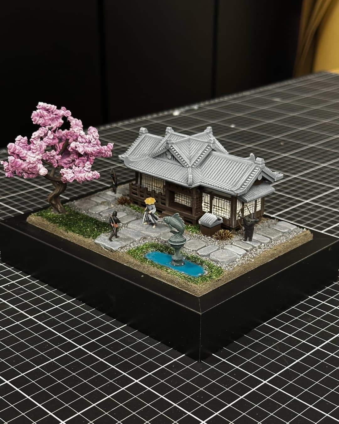 Diorama of a Japanese house with a cherry blossom tree, a pond and samurai figures
