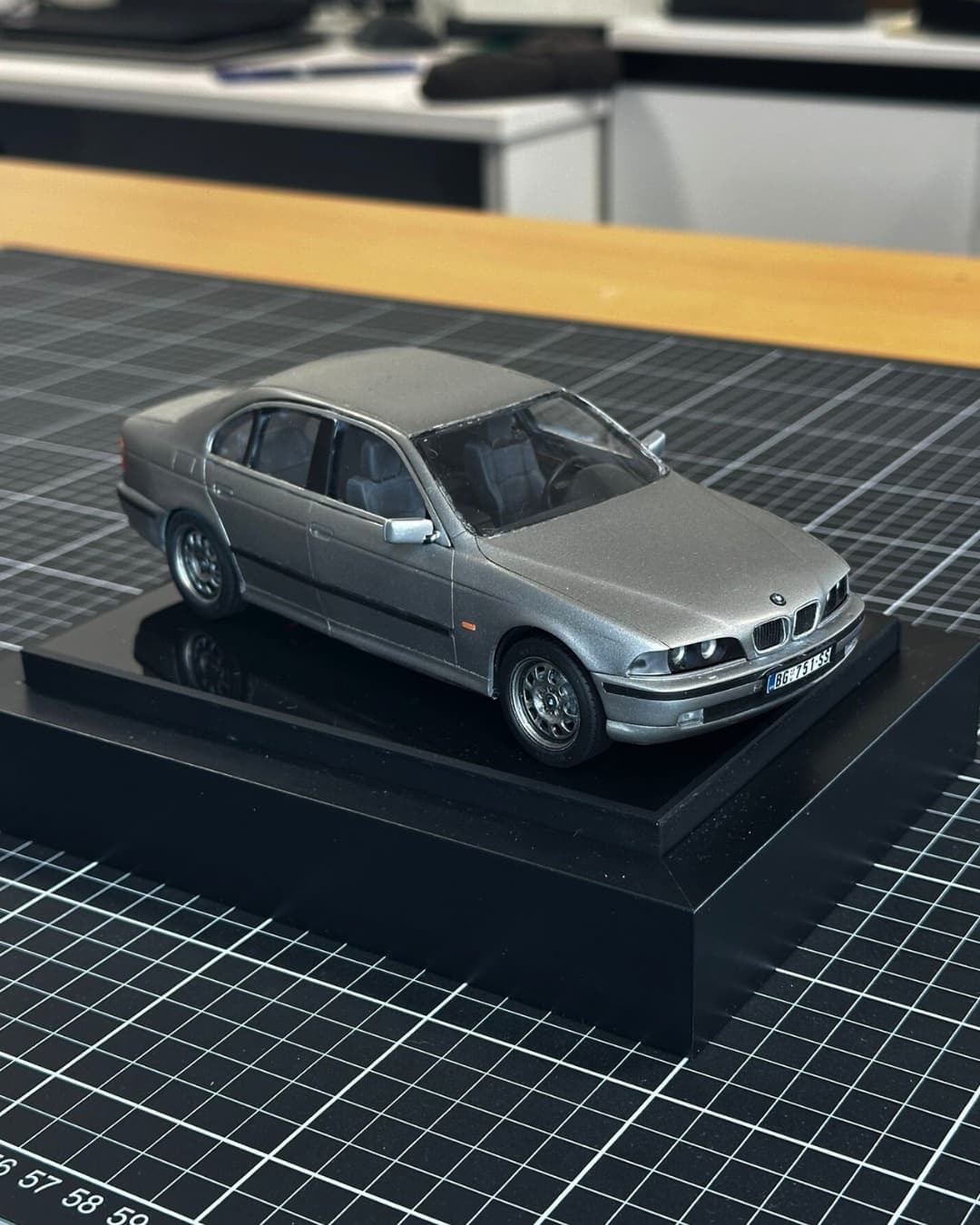 Scale model of a silver BMW 5 Series sedan on a black display base